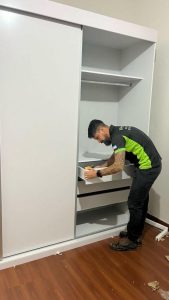 Trabalhador uniformizado da FR Montagens montando guarda-roupa